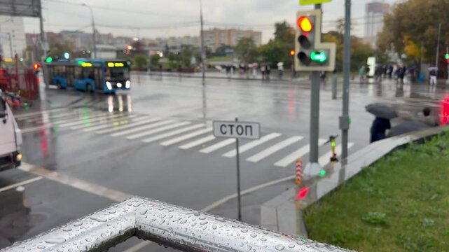 Pedestrian zebra crossing under rain with green arrow traffic signal and Russian stop line sign. Urban city environment, rainy autumn weather, wet road infrastructure with reflections. Slowmo, blur