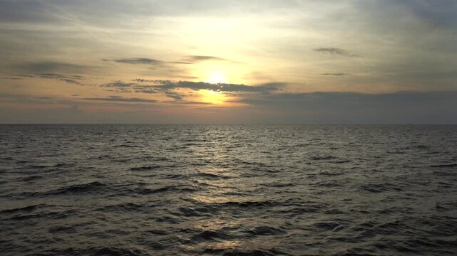 View of the sun setting over the calm waters of the Andaman Sea near Lam Kaen, Phang Nga, Thailand.