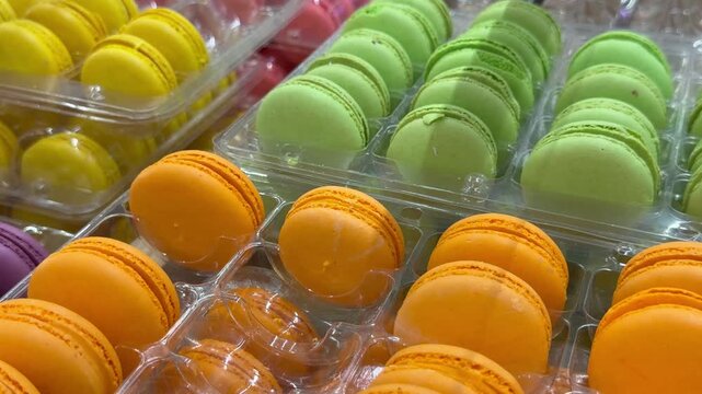 Rows of colorful french macarons in a bakery display case. Sweet pastry dessert, delicious treats, cafe selection.