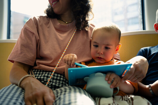 Toddler using digital tablet with mother on public transport