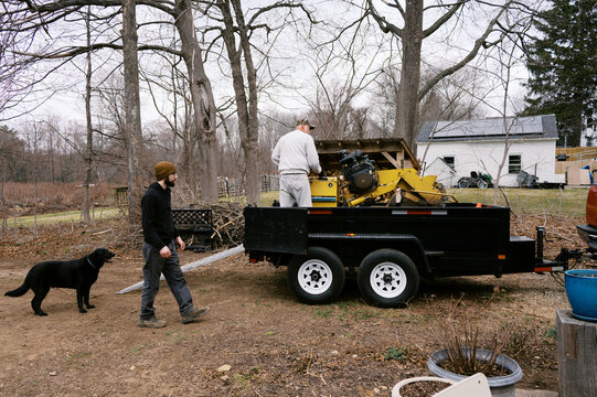 working men talking while loading machinery onto trailer