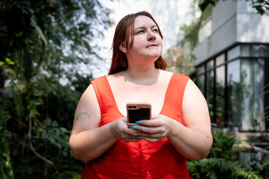 Gen Z girl with red hair and bangs texts friends on a fold phone