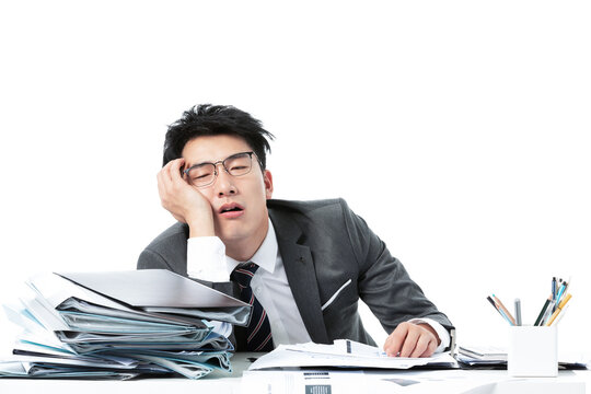 Exhausted Asian businessman sleeping at desk overwhelmed by paperwork