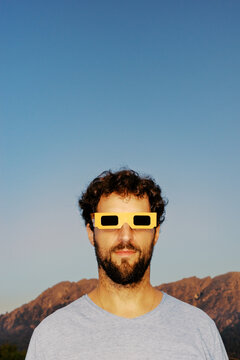 Man wearing unique glasses stands against a clear sky