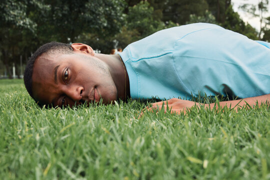 Young man relaxing on green grass in park