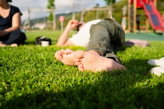 Person relaxing barefoot on green grass in park