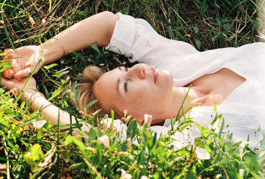 A woman lies in a wildflower meadow in a white dress