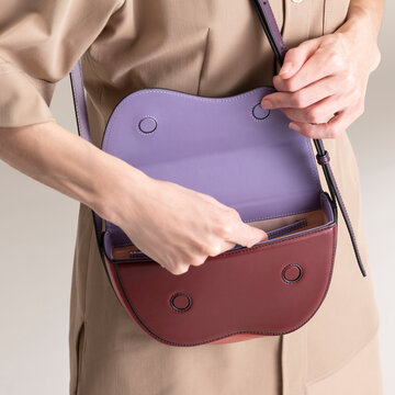 Purple Leather Handbag Held Against Neutral Trench