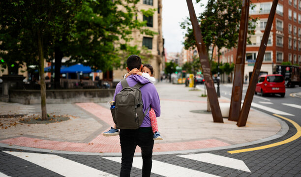 Father carrying small child on city street