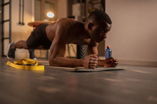 Determined African American sportsman doing plank at home