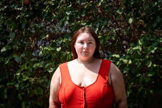 Portrait of a plus-size Gen Z girl in a red dress outdoors in summer