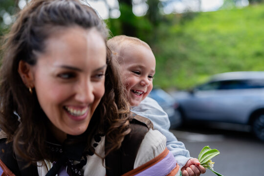 Mother giving piggyback ride to laughing child outdoors