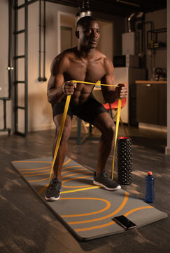 Black sportsman exercising with resistance band online at home