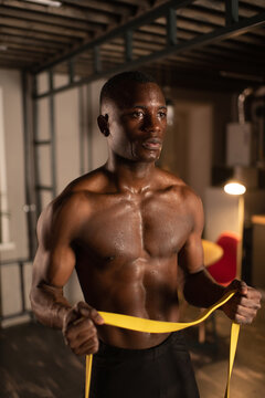 African American sportsman exercising with resistance band at home