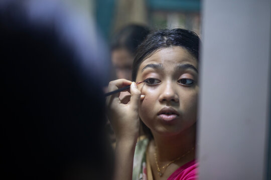 Young Indian woman doing self make up inside home