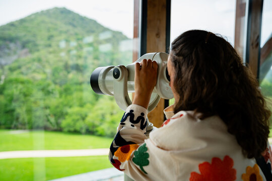 Woman observing nature landscape through public binoculars