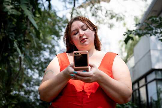 Redhead Gen Z girl with bangs posts on social media from a fold phone