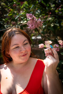 Plus-size Gen Z girl in a red dress beneath a blooming flower tree