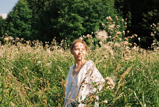 A woman stands among wild thistles in a summer meadow