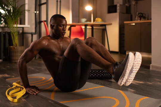 Strong black athlete doing abs exercise at home