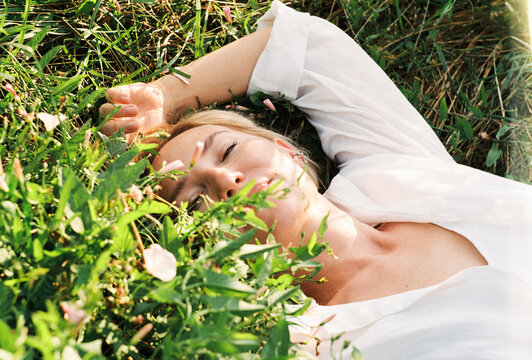 A young woman lies in tall grass among wildflowers