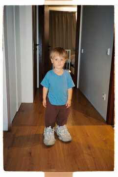 Toddler standing in oversized adult shoes at home
