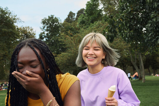 Friends laughing and enjoying ice cream in a park