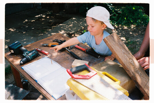 Toddler helping with a woodworking project at an outdoor table
