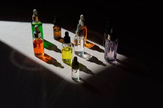 Colorful Serum Dropper Bottles in Sunlight and Shadows with Copy Space