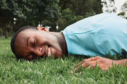 A smiling young man lying face down on the grass