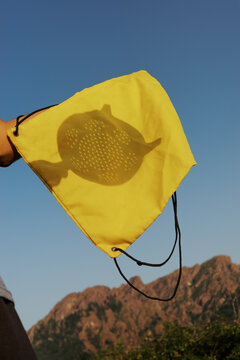 Holding a yellow bag with a shadow in the sun on a mountain