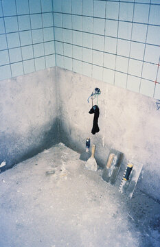 Tiling Tools Resting Against Concrete Wall in Unfinished Kitchen