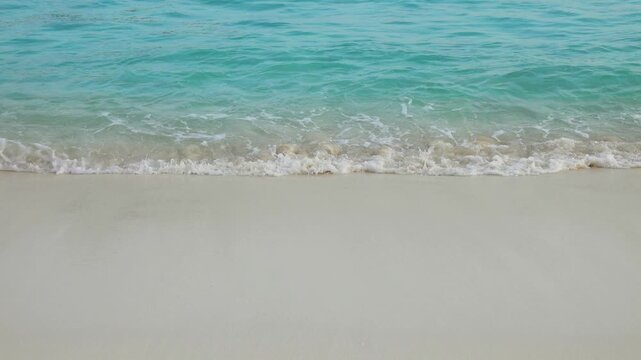 View of turquoise water washing over the white sand beach at Similan Islands in Lam Kaen, Phang Nga, Thailand.