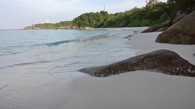 View of the white sand beach at Similan Islands with large granite boulders, turquoise water, and lush tropical vegetation in Lam Kaen, Phang Nga, Thailand.