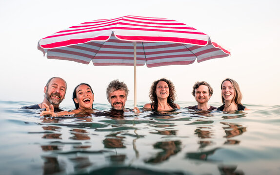Friends Laughing Together Under a Beach Umbrella at Sea