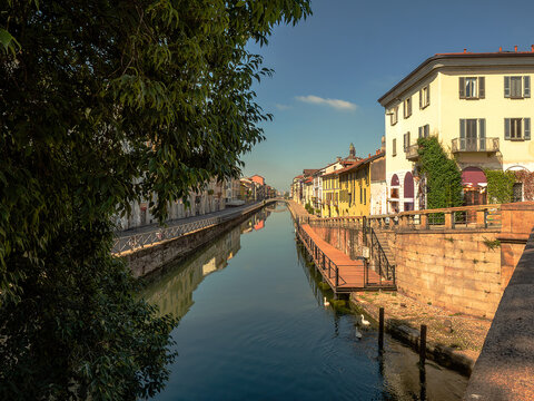 A view of Milan's canal, lined with bars and small restaurants under a clear sky