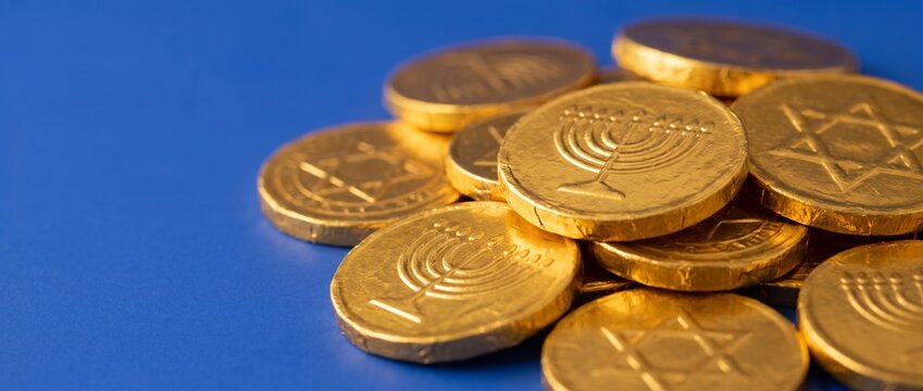 Gold coins with menorah and star designs on a blue background  