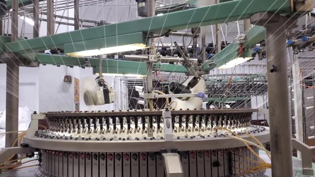 Circular Knitting Machine Needles Operating At High Speed In Textile Factory
Close-up view of a circular knitting machine's needle bed operating at high speed with yarn feeding from top. 