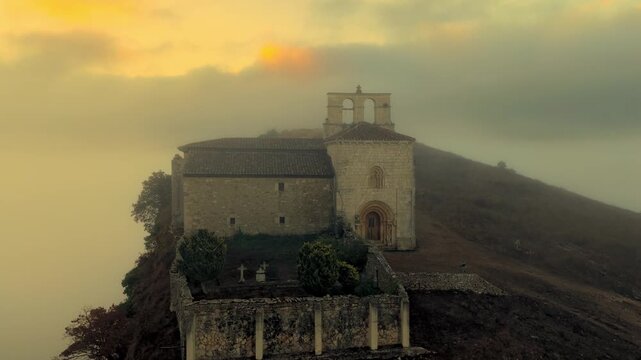 Peque&ntilde;a iglesia rom&aacute;nica de piedra construida sobre una colina rocosa con forma de barco al amanecer, con niebla en el Valle de Losa, Arquitectura medieval antigua, templo hist&oacute;rico rural, Pantale&oacute;n.