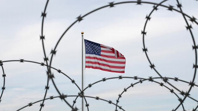 American flag through barbed wire on flagpole, symbolic image