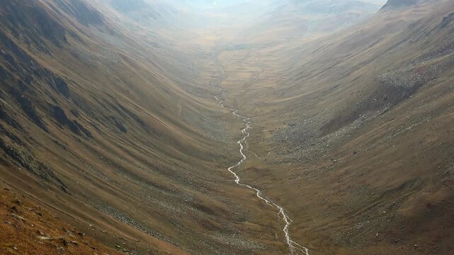 Peru mountain valley landscape shows glacial shaped slopes and winding stream below.