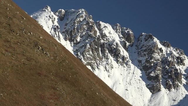 Snowy Alpine peaks above treeless high altitude meadows create striking mountain scenery.