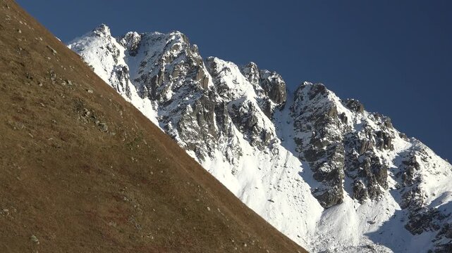 Snowy Alpine peaks above treeless high altitude meadows create striking mountain scenery.