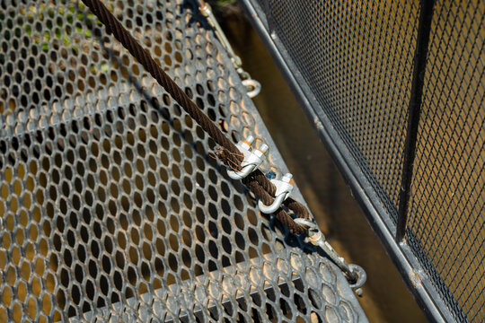 Detailed view of rusted metal clamps. Closeup of metal cable fittings with textured surface. Focus on corroded metal connectors with textured decking during maintenance inspection