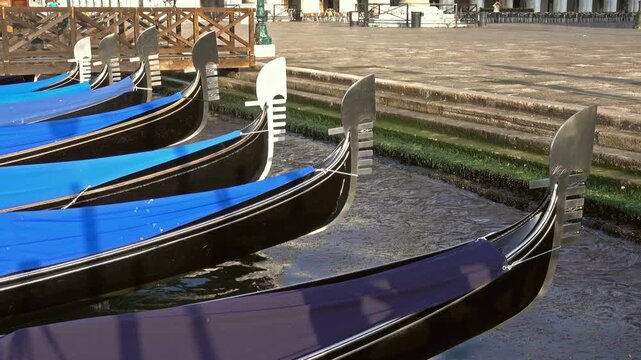 View of traditional black gondolas moored in a canal with blue covers in Venice, Veneto, Italy.