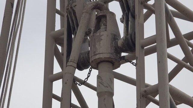 Drilling motor and rotating pipe mechanism on well rig tower during borehole excavation.