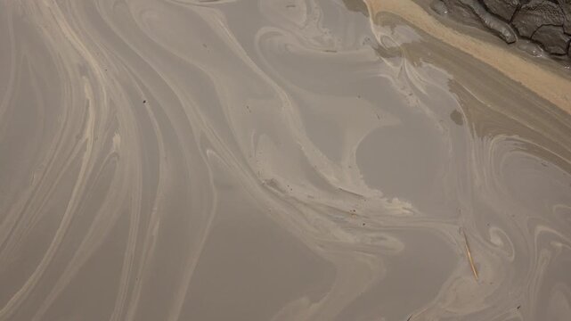 Muddy water swirls with thick sediment during industrial drilling activity.