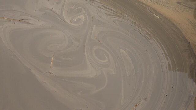 Muddy water swirls with thick sediment during industrial drilling activity.