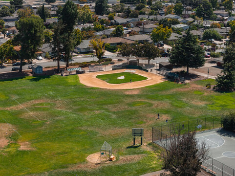 Aerial shot of an empty baseball field, adjacent court, and community park borders in Cupertino, California, showing residential homes and trees.