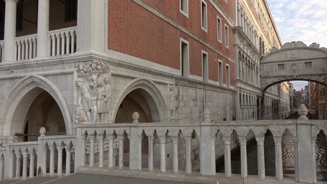 View of the historic Doge's Palace and the iconic Bridge of Sighs featuring intricate Gothic stone carvings and canal views in Venice, Veneto, Italy.